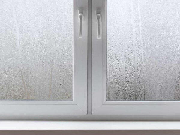 A white UPVC window with condensation on it